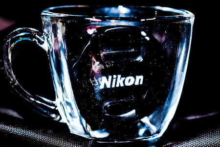 Close Up Photo Of Clear Glass Mug With Nikon Lens Cap