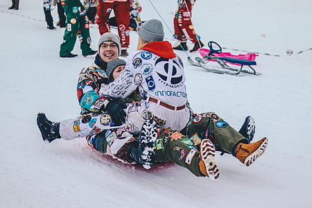 three people riding snow sled