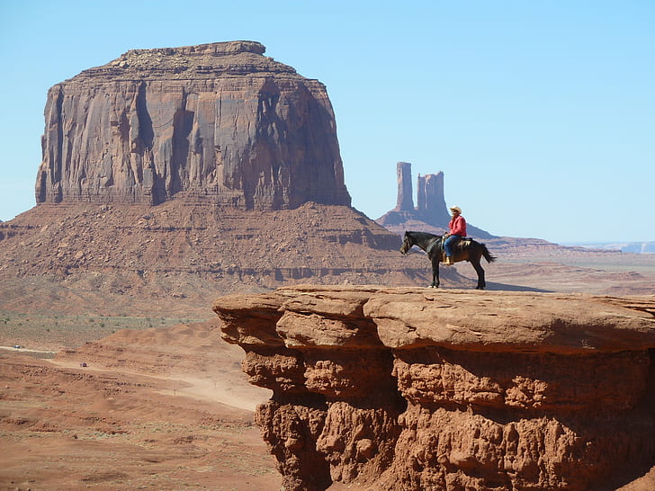 man riding on horse near rock cliff near canyon