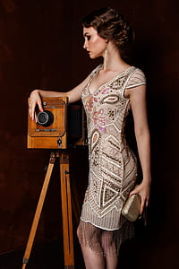 woman in gray and brown paisley scoop-neck dress standing near brown camera