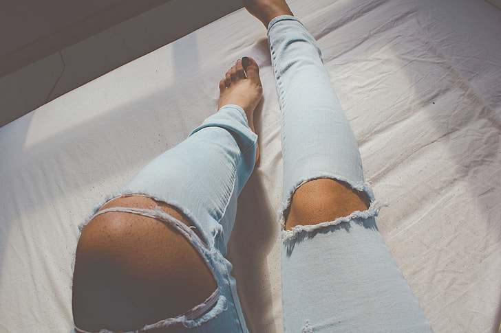 A woman’s legs wearing blue denim jeans
