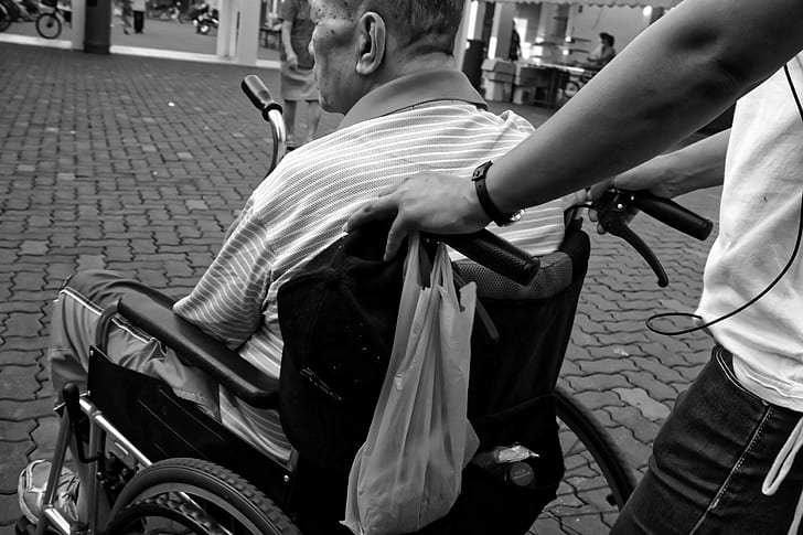 grayscale photo of man sitting in wheelchair