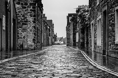 grayscale photo of stone wall alley