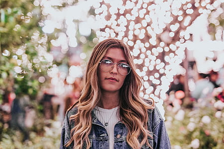 selective focus photography of woman wearing eyeglasses and blue denim jacket