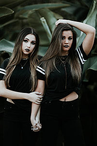 two women in black sleeve crop top and black pants holding hands