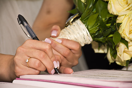 woman writing on pink notebook
