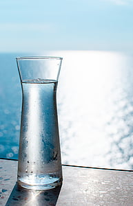 clear glass vase with cold water inside near body of water during daytime
