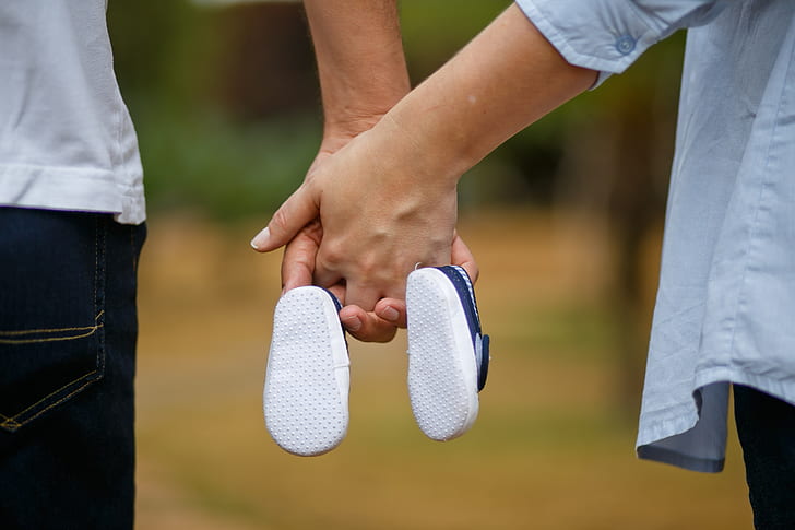 man and woman holding hands and holding pair of blue shoes