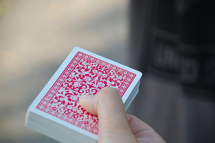 person holding red and white playing card deck