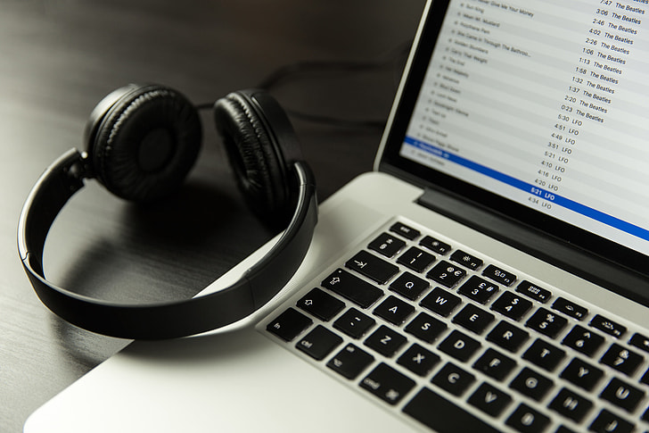 iTunes music app open on a laptop computer alongside headphones