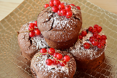several brown cupcakes with red berries on top