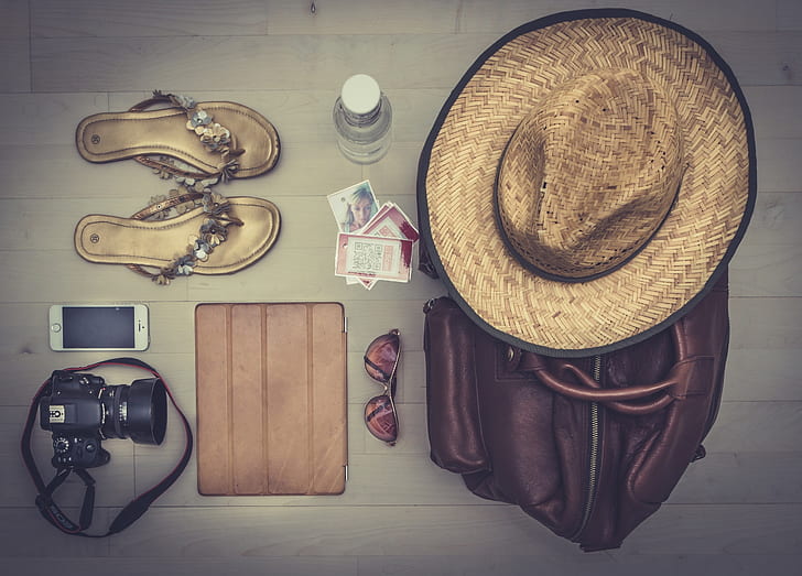 photography of brown hat on brown leather bag besides sunglasses, leather sandals, DSLR camera and silver iPhone 5s