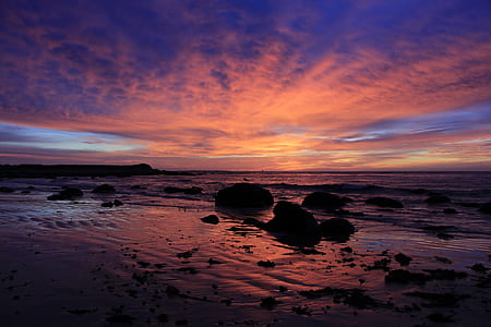 silhouette of rocks on seashore against sunlight