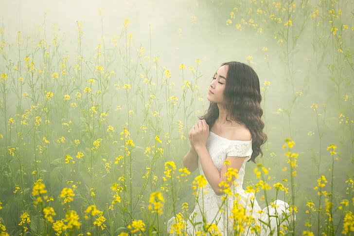 woman wearing white lace off-shoulder dress on yellow rapeseed flower field