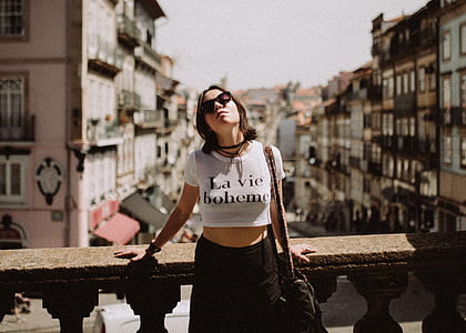 woman wearing white and black crop-top standing near brown concrete balustrade