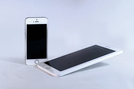 Silver Iphone 5s and White Samsung Android Smartphone