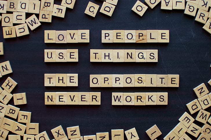 brown wooden scrabble chips forming love people use things the opposite never and works letters