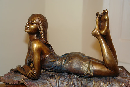 woman lying on stomach brass-colored figurine