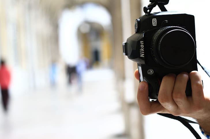 person holding black Nikon D70 in tilt shift lens photography
