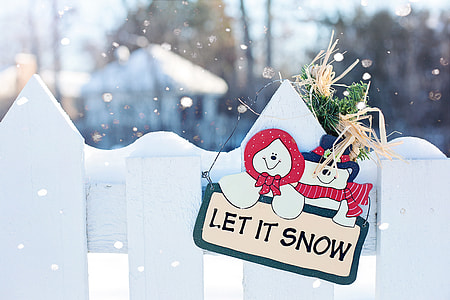 Let It Snow signage hanged on white wooden fence