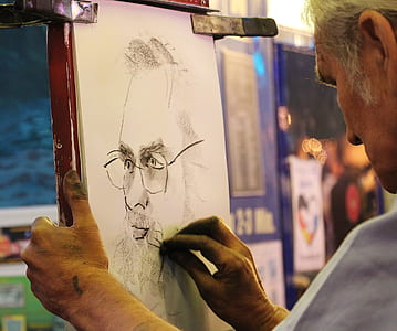 man sketching bearded man on white paper