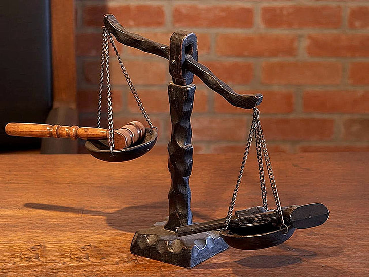 black balance scale with gavel and pistol
