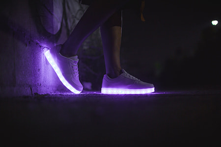 person wearing white LED low-top sneakers
