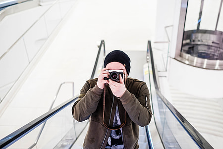 man holding SLR camera on escalator