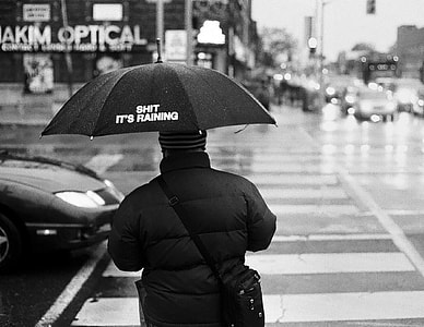 person wearing jacket holding umbrella during rainy day