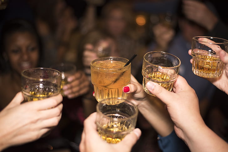 selective focus photography of person holding shot glasses