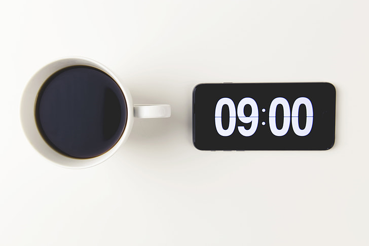 Cup of coffee with the time displayed on mobile iPhone smartphone clock