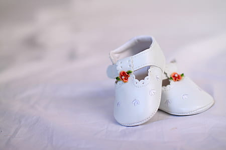 pair of baby's white shoes on white textile