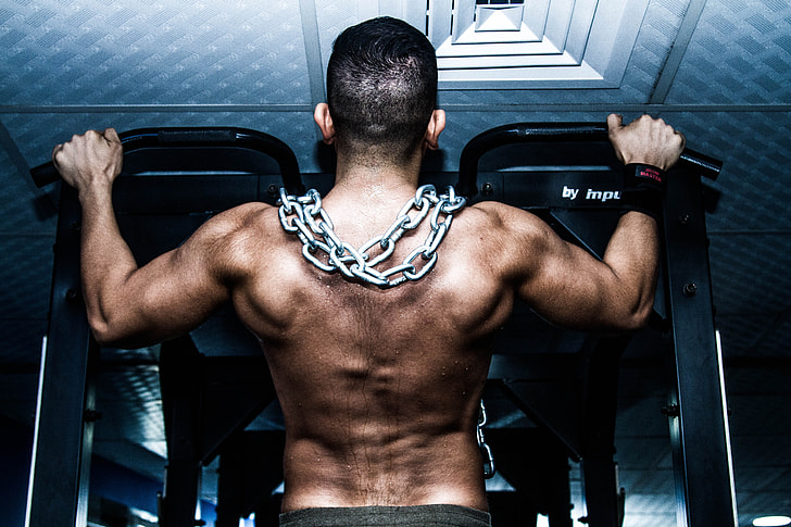 man pull his self on black pull up bar with chains on his shoulder
