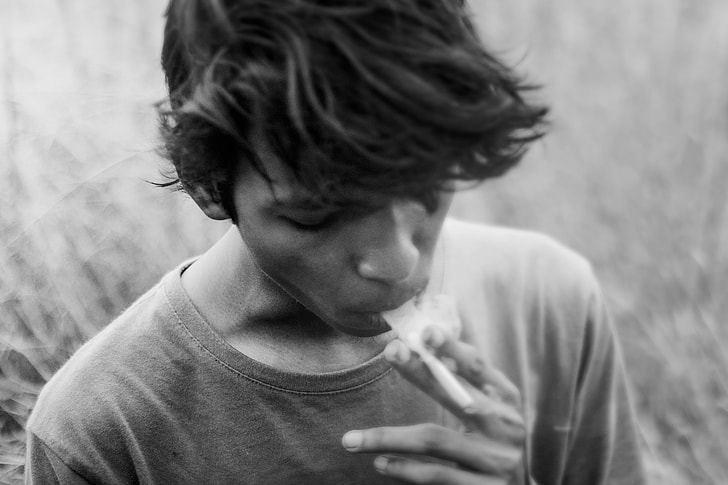 gray scale photo of man smoking cigarette