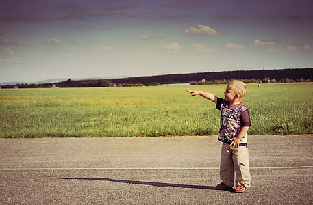 boy standing at pathway raising right hand