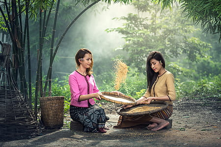 two woman sitting on stones holding basket