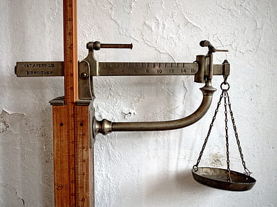 brass-colored beam balance scale mounted on wood