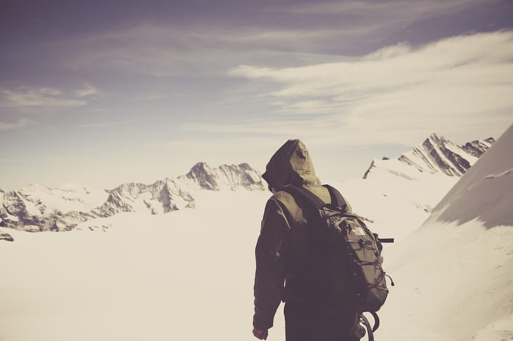 photo of person with hiking backpack on mountains filed with snow