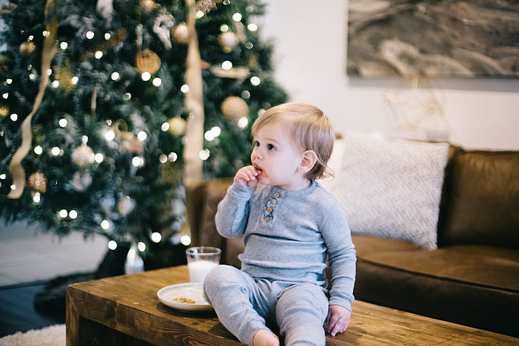 baby wearing gray long-sleeved shirt and pants sitting on brown wooden coffee table