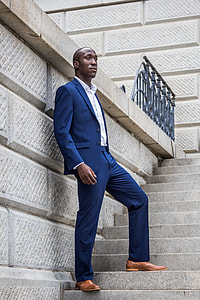 man in blue 2-piece suit standing on staircase