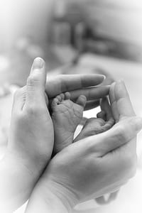 person's hand holding baby's feet