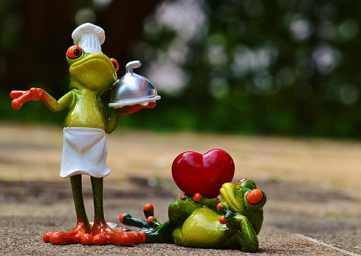 bokeh shot of two green chef frogs figurines