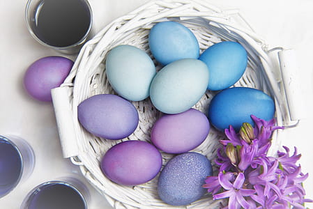 assorted painted eggs on round white wicker basket