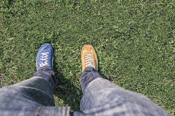 person in gray denim jeans standing on green grass during daytime