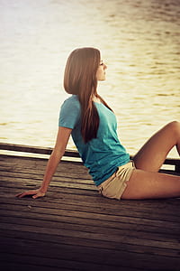 woman wearing blue v-neck shirt sitting on dock