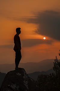 silhouette of man standing on mountain cliff