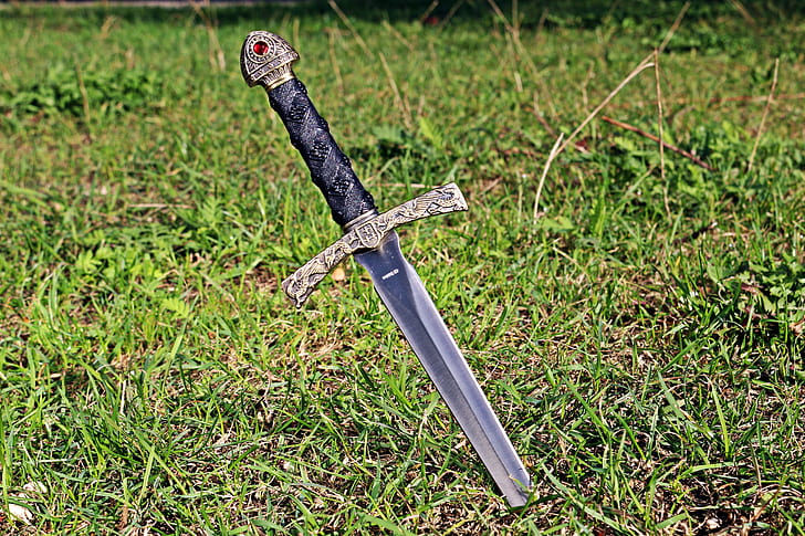 black and grey sword in green grass