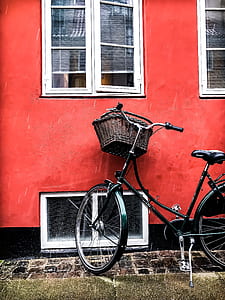 black city bicycle beside red wall