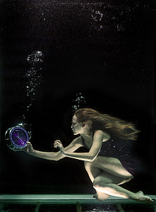 woman holding desk clock underwater
