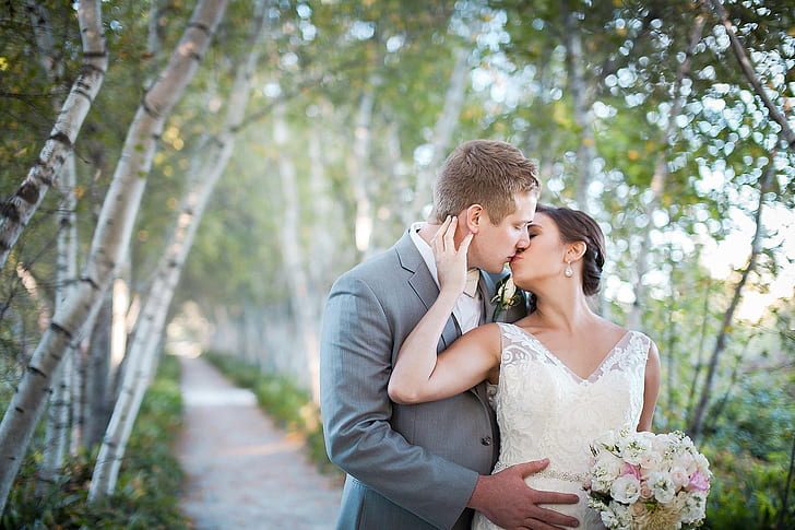 man kissing woman wearing white wedding dress